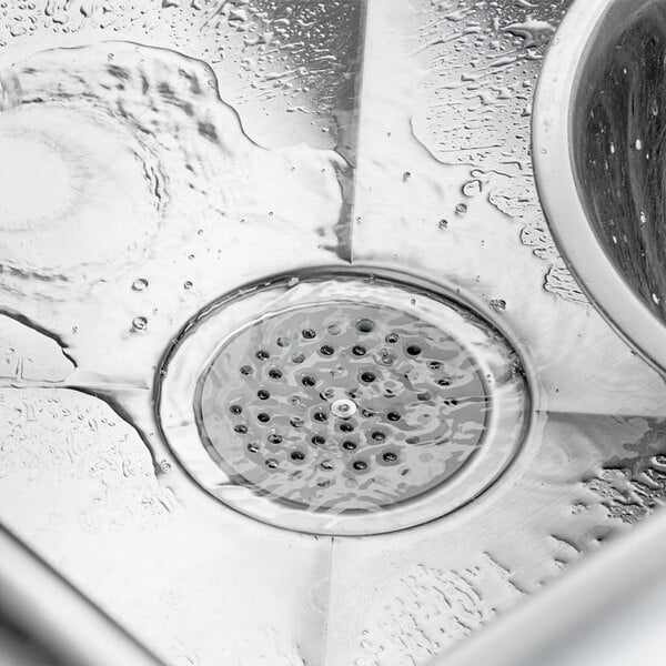 A Regency ScrapLock drain strainer in a sink with water running down the drain.