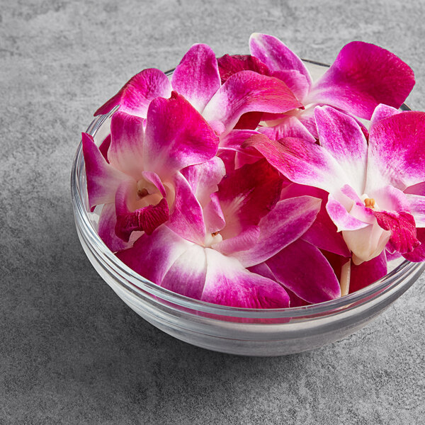 A bowl of pink and white orchids on a table.