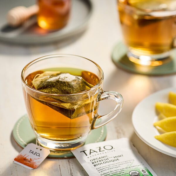 A glass cup of Tazo Organic Refresh Mint tea with a tea bag in it.