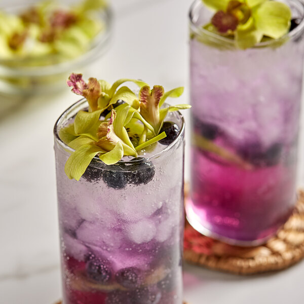 A glass of purple drink with a Green Orchid flower on top.