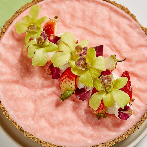 A pink cake with green orchids on top.