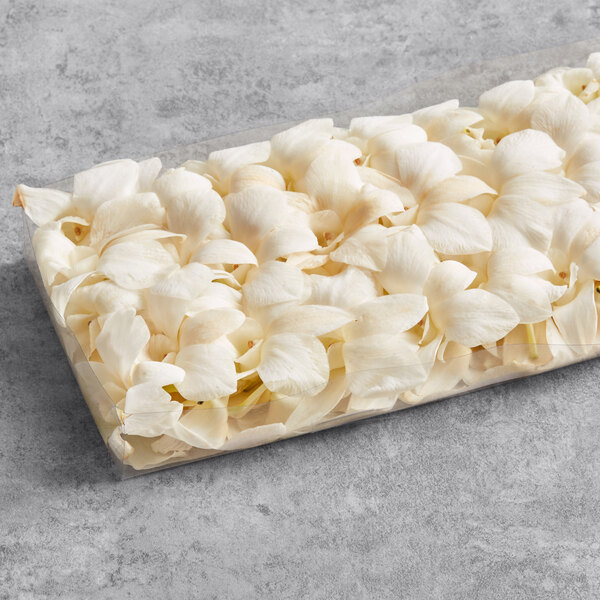 A rectangular plastic container filled with white orchids.