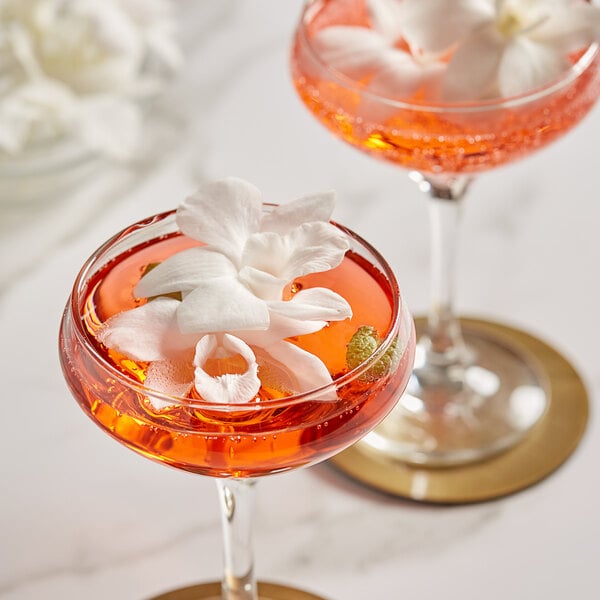 Two glasses of a white drink with White Orchids as garnish.