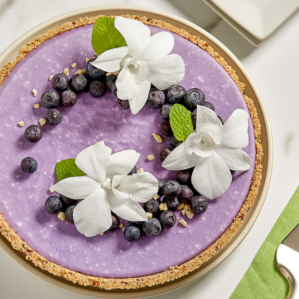 A pie with blueberries and white White Orchid flowers on top.