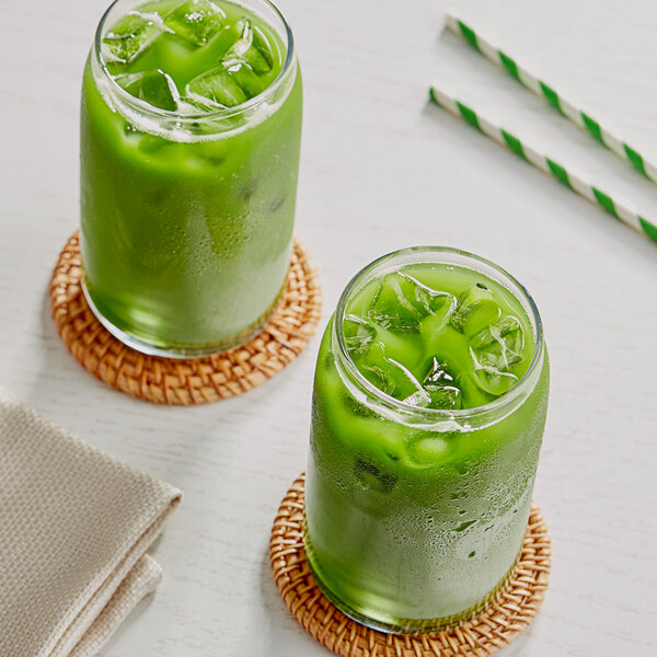 Two glasses of Tenzo matcha green liquid with ice and straws.