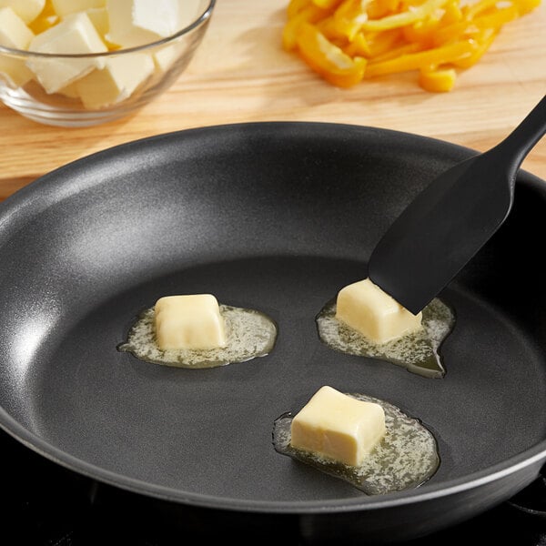 A pan with Grassland butter and a spatula on a stove.