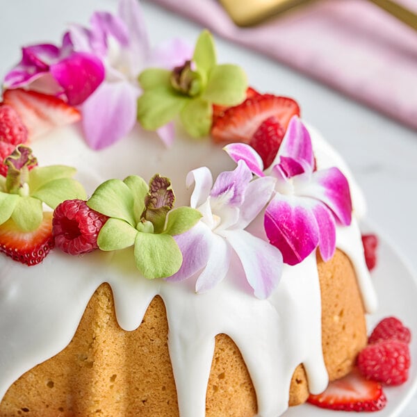 A bundt cake with mixed color orchids on top.