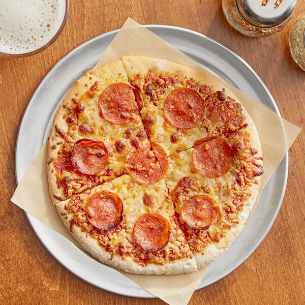 An 8" Pizzeria Uno pepperoni pizza on a plate with a glass of beer on a table.