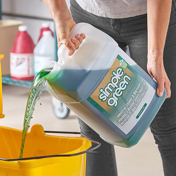 A person pouring Simple Green Sassafras Scented Concentrated Industrial Cleaner and Degreaser into a bucket.