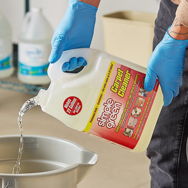 A gloved hand pouring Simple Green Pro carpet cleaner into a container.