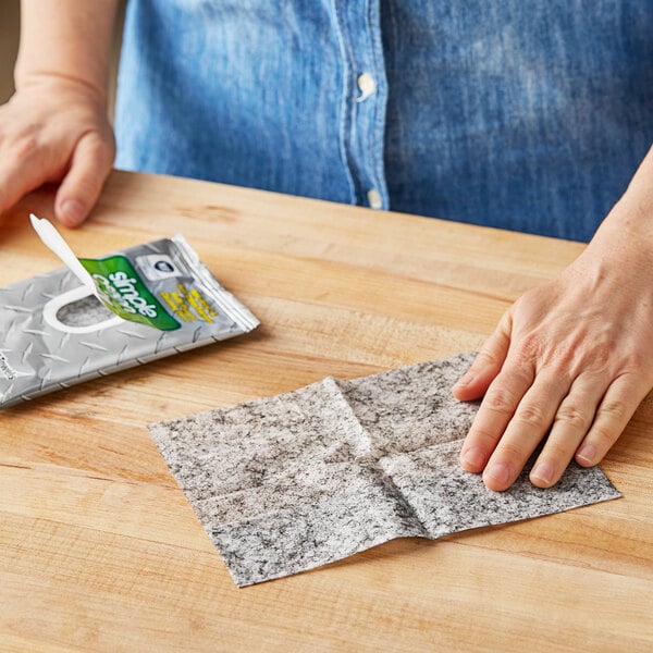 A hand using a Simple Green Safety Towel to clean a table.