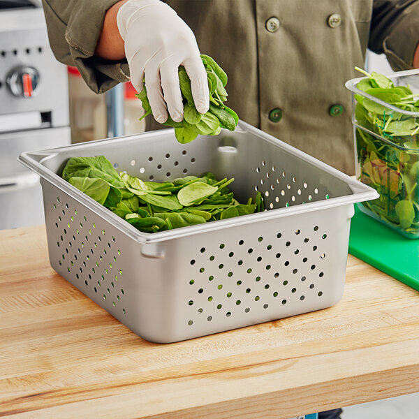 A metal container of spinach leaves being filled.
