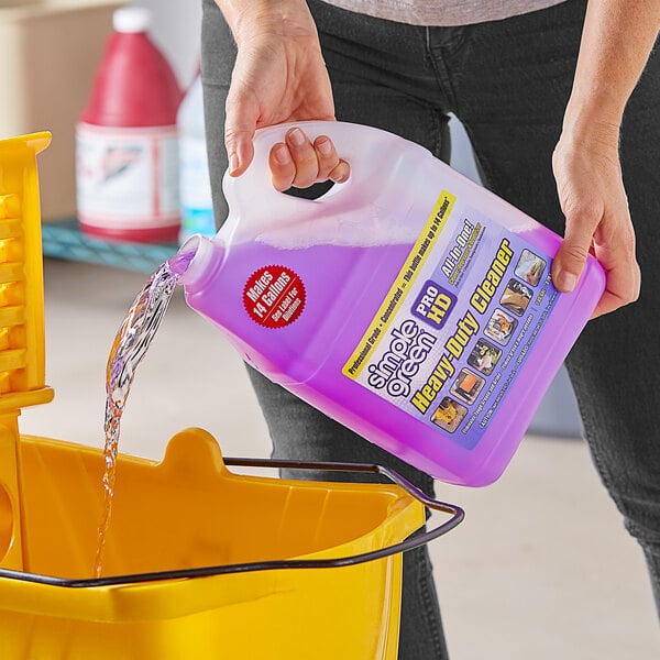 A person pouring Simple Green Pro HD cleaning liquid into a yellow bucket.