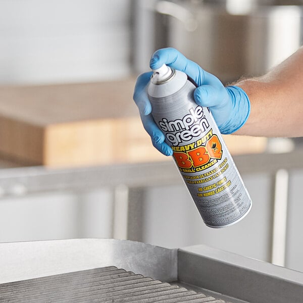 A person in blue gloves using Simple Green BBQ and Grill Cleaner to spray a grill.