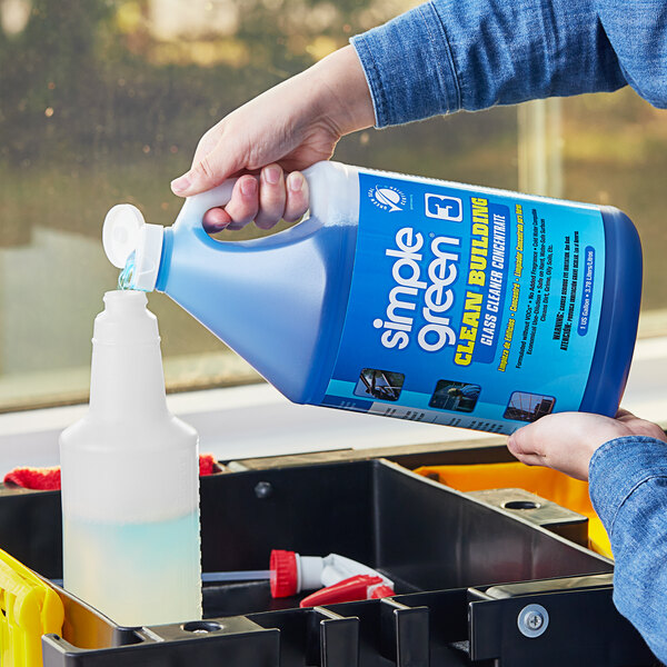 A person pouring Simple Green Concentrated Glass Cleaner from a blue bottle into a container.