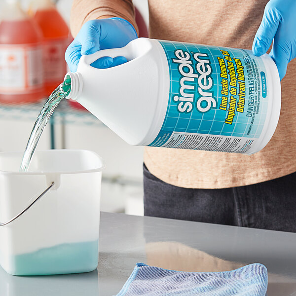 A person in blue gloves pours Simple Green Lime Scale Remover into a container.