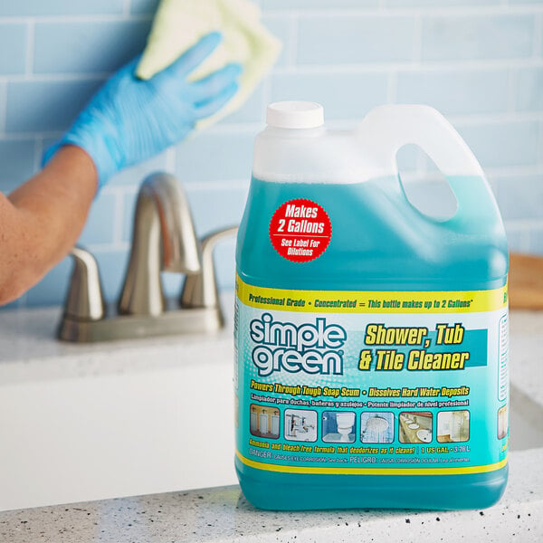 A person holding a bottle of Simple Green shower cleaner on a kitchen counter.