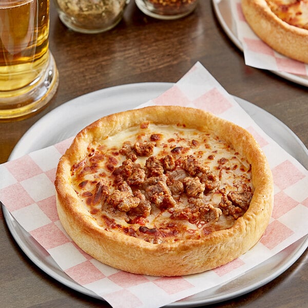 Two Pizzeria Uno deep dish sausage pizzas on a table with a glass of beer.