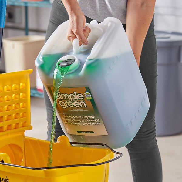 A person pouring green Simple Green liquid into a container.