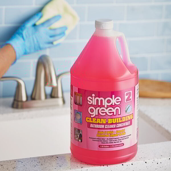 A person holding a bottle of Simple Green Clean Building concentrated bathroom cleaner on a counter.