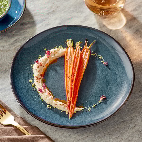 A Acopa Highlands skyfall blue coupe china plate with carrots and hummus on a table with a fork on a napkin.
