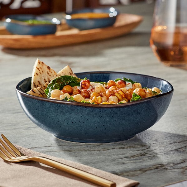 A skyfall blue china bowl filled with food on a table.