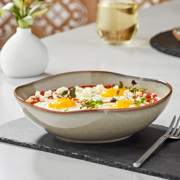 An Acopa Highlands heather gray china bowl filled with food on a table with a fork.