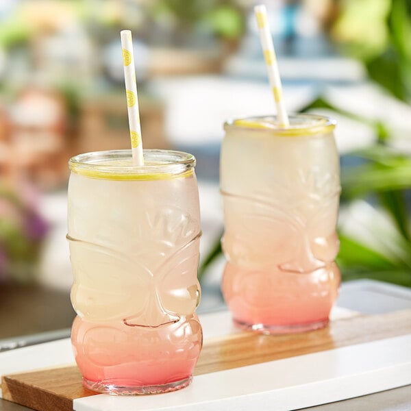 Two glasses of Tiki Breeze Clear Energy Shots with straws on a table.