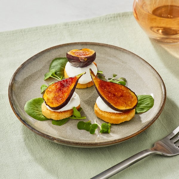 A plate of figs and cheese on a Acopa Highlands heather gray china plate with a fork next to a glass of wine.