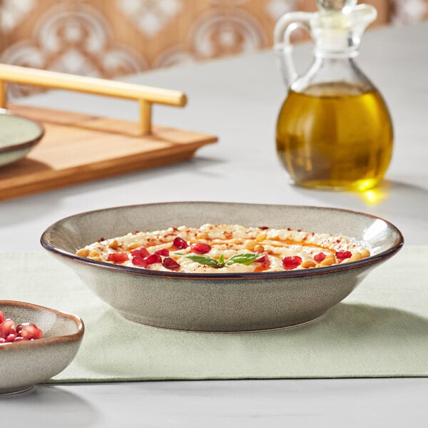 A bowl of food with pomegranate seeds in an Acopa Highlands heather gray china bowl on a table.