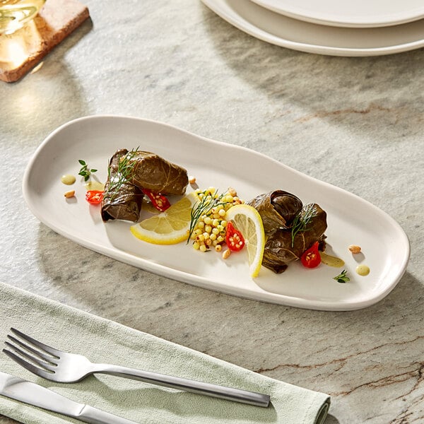 A rectangular white Acopa China tray with food on it and a fork and knife.