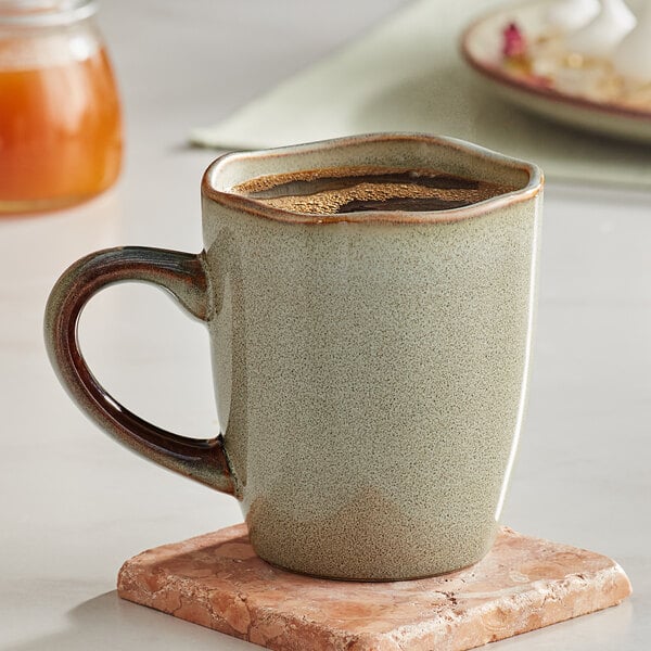 A Heather Gray Acopa Highlands China mug on a marble table with a cup of coffee on a coaster.