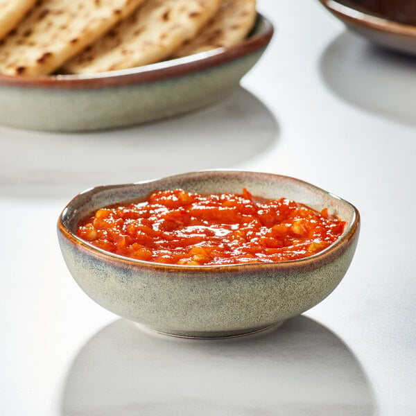 An Acopa Highlands heather gray china sauce cup filled with red sauce on a table with flat bread.