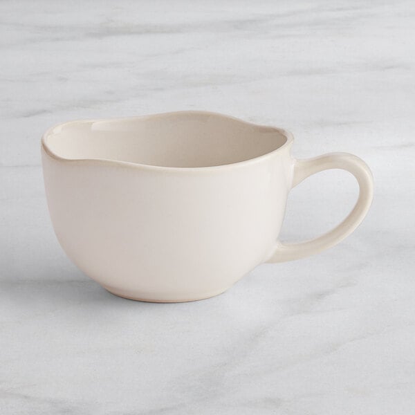 An Acopa Highlands white china cup with a handle on a marble surface.