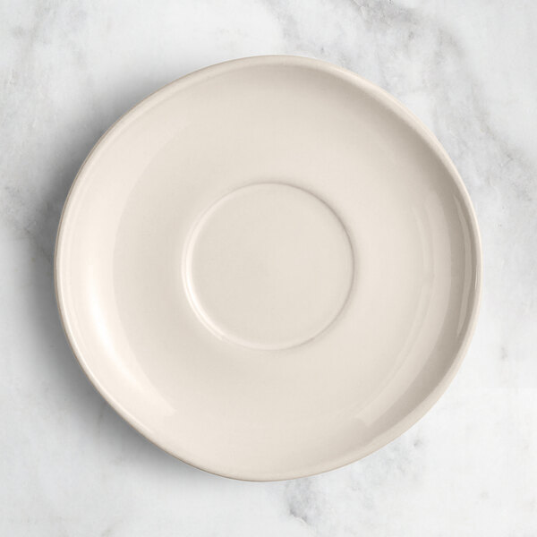 An Acopa Highlands white saucer on a marble surface.