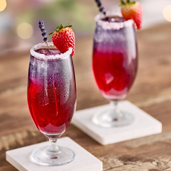 Two glasses of Tiki Breeze pink drink with strawberries on top.