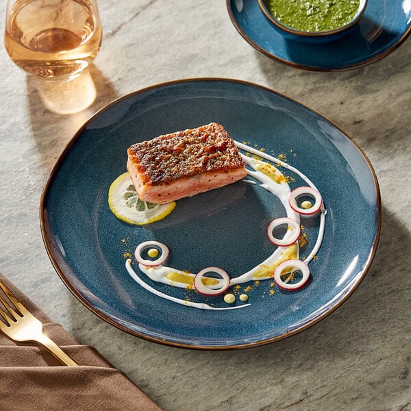 A Acopa Highlands skyfall blue coupe china plate with a piece of meat and green sauce on a table with a fork on a napkin.