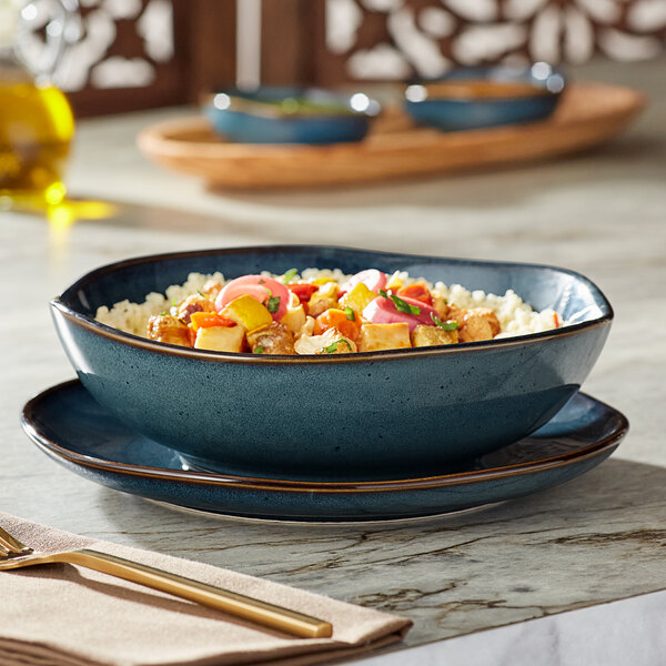 A blue Acopa Highlands china bowl filled with rice and vegetables on a table.