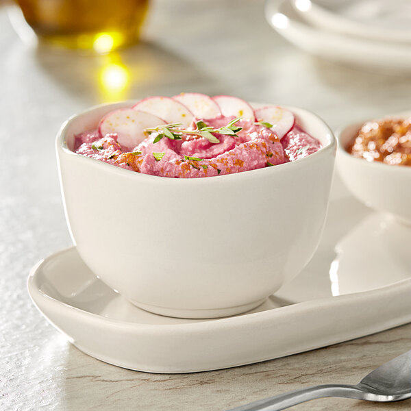 An Acopa Highlands white china bouillon cup filled with pink soup on a table.