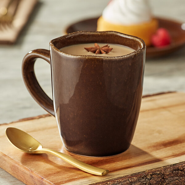 An Acopa Highlands hazel china mug on a wood table with a star anise and a gold spoon in it.