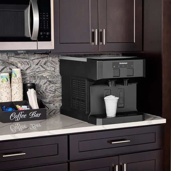 A Scotsman Meridian nugget ice machine on a counter with a cup of ice.