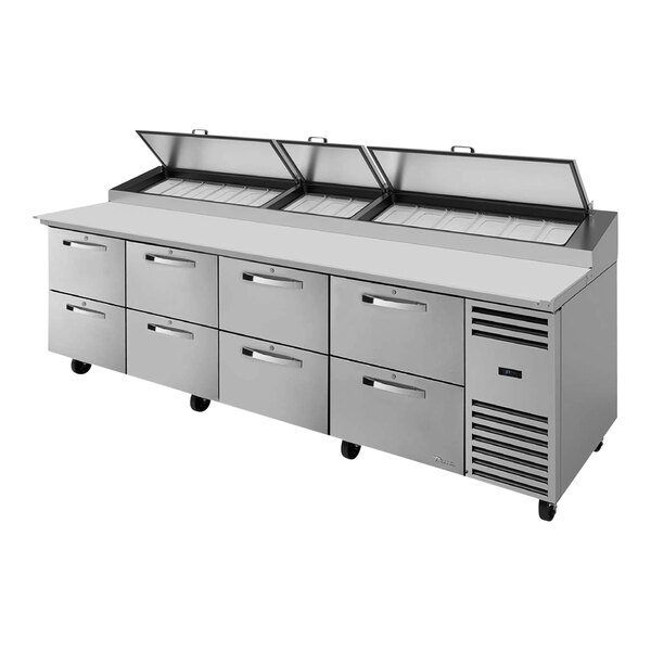 A black and silver True refrigerated pizza prep table with eight drawers open.