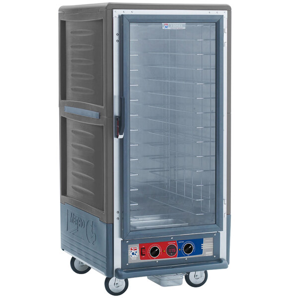 A large grey Metro holding and proofing cabinet with a clear door on wheels.