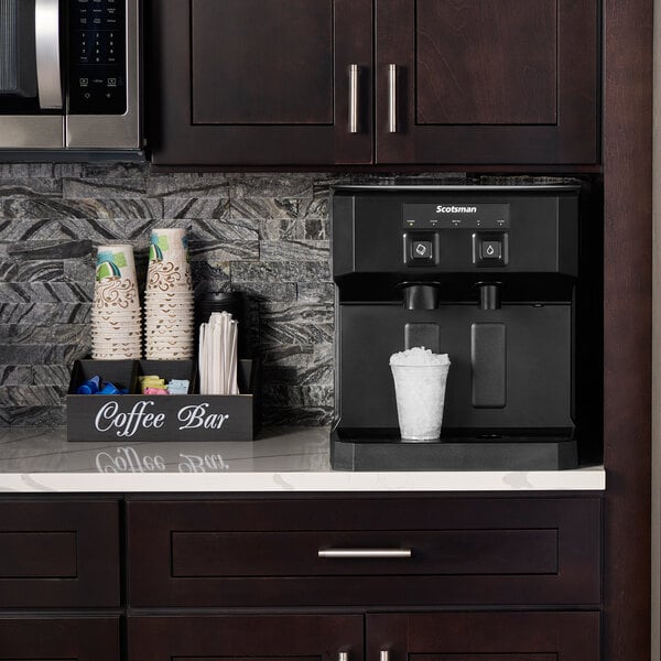 A Scotsman Meridian ice and water dispenser on a counter with a white cup of ice.