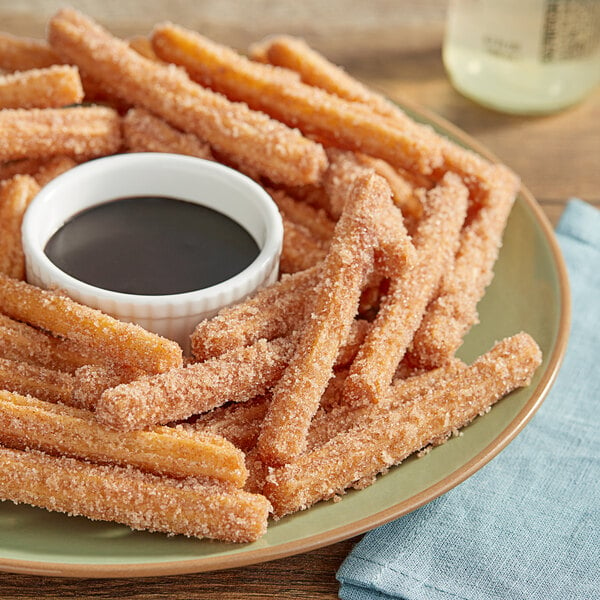 A plate of Hola Churro Fries with cinnamon sugar topping and dipping sauce.