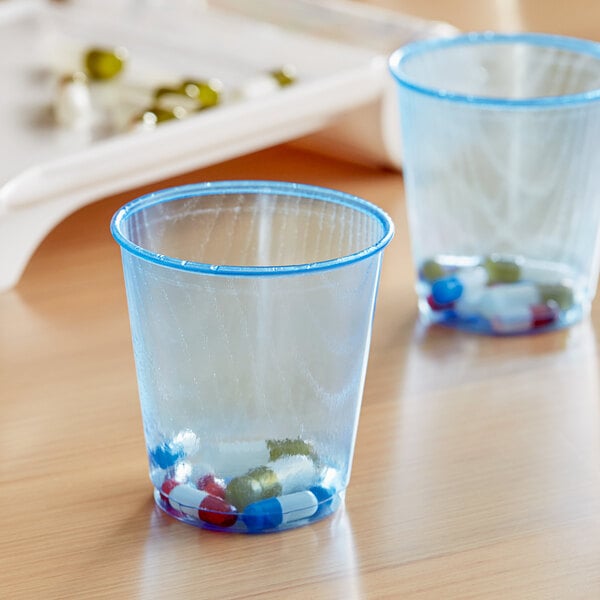 A pair of Solo cobalt blue plastic cups with pills inside.