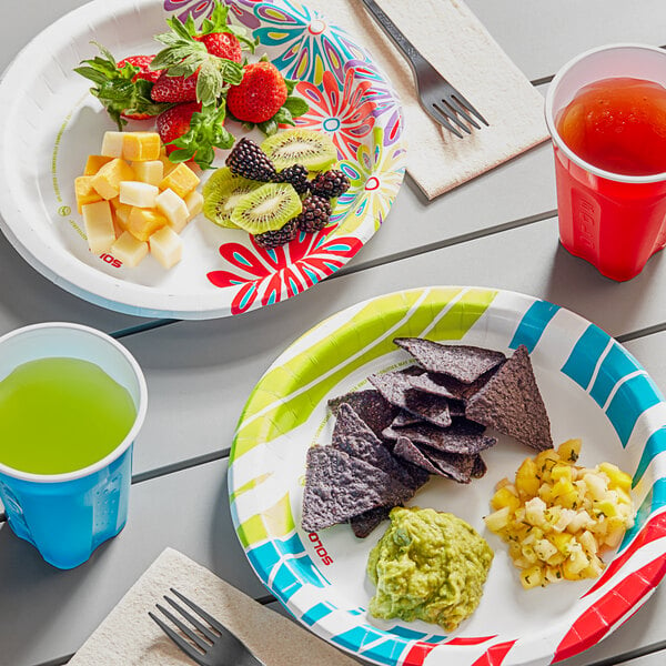 A table with Solo AnyDay paper plates of food and drinks on it outdoors.