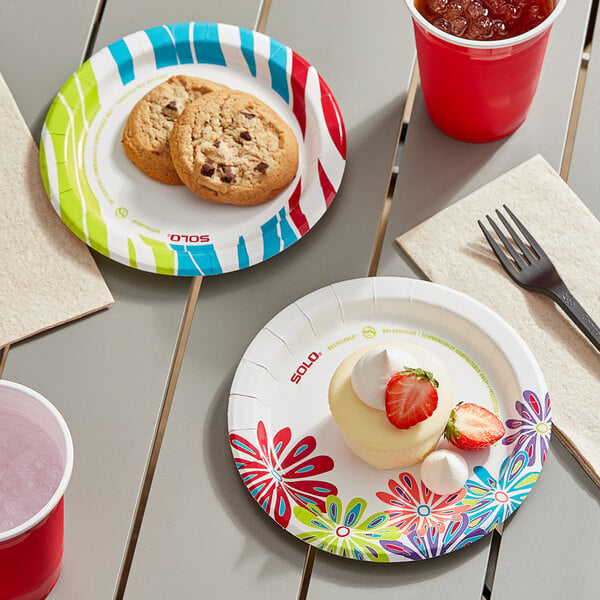 A table set with Solo AnyDay Lush Blooms and Wavy Tropics paper plates, a red cup, and cookies.