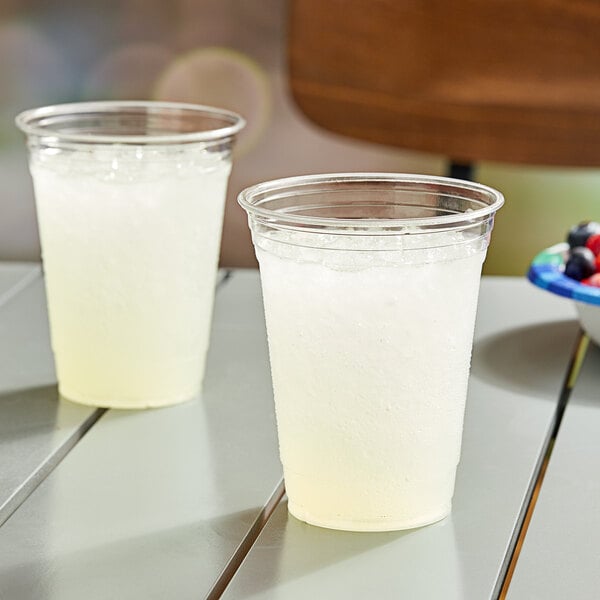 Two Solo clear plastic cups filled with a white liquid on a table.