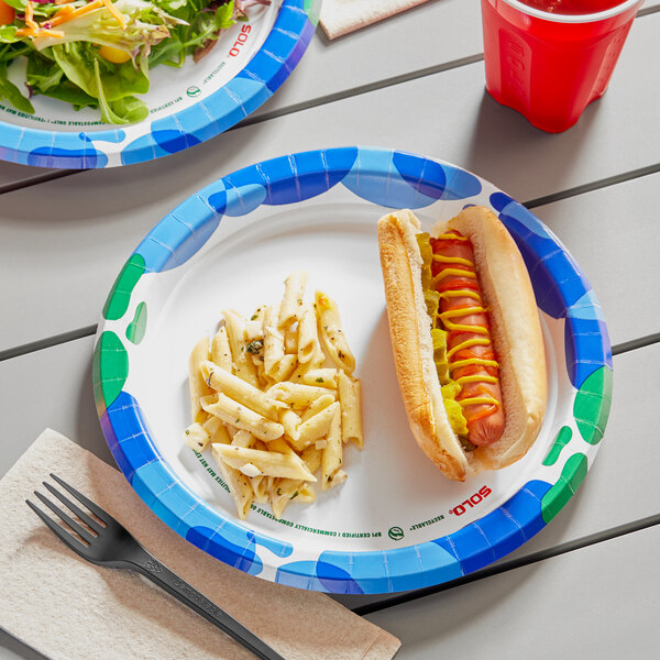 A Solo sea glass paper plate with a hot dog, pasta, and a fork on a table.